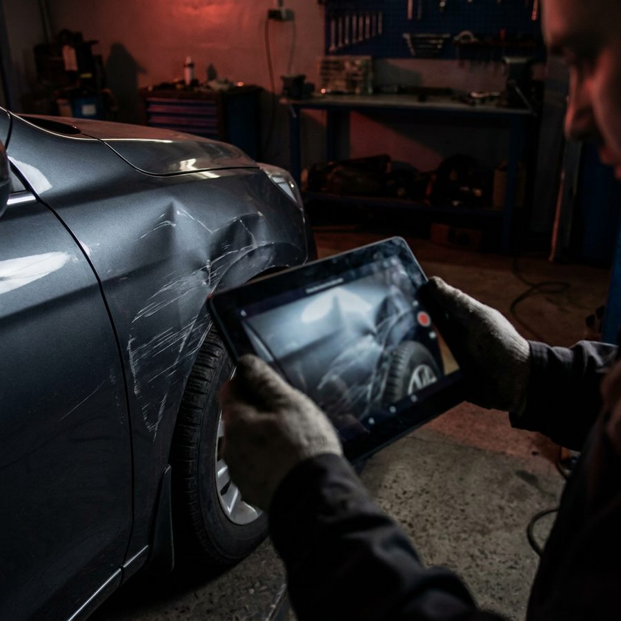 Schadendokumentation mit Tablet an einem beschädigten Kotflügel